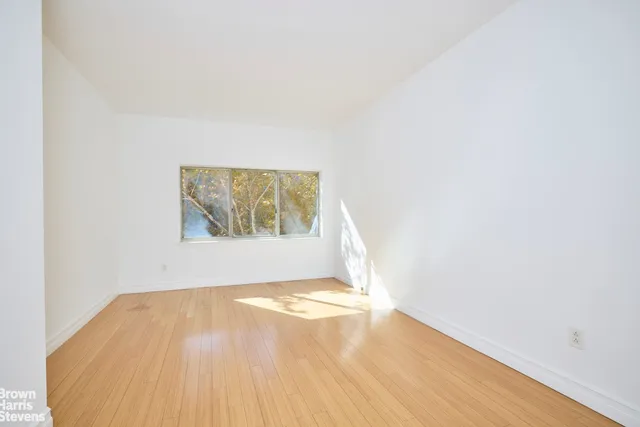a view of a big room with wooden floor and windows