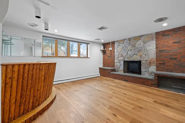an empty room with wooden floor fireplace and windows