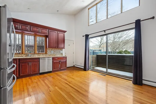 a large kitchen with stainless steel appliances wooden cabinets a sink and a large window