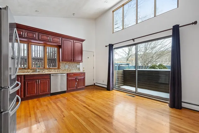 a large kitchen with stainless steel appliances wooden cabinets a sink and a large window