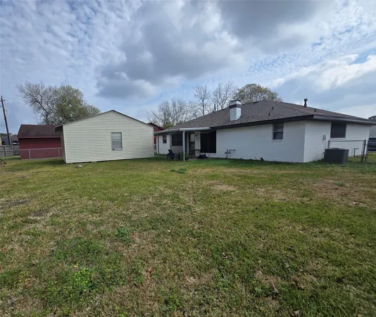 a view of a house with a yard and a large tree