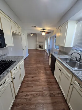 a large kitchen with granite countertop a lot of counter space and wooden floor