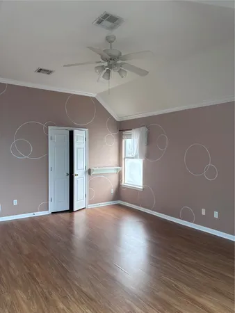 a view of empty room with wooden floor and fan