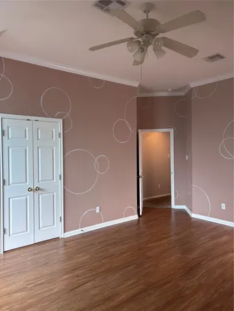 an empty room with wooden floor chandelier fan and windows