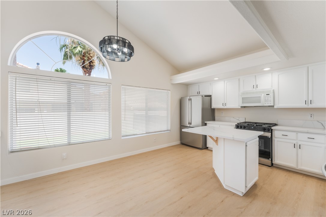 8872 Chapman Point Las Vegas, NV 89129 - Photo 7 of 29 Voluminous ceilings elevate this kitchen's bright atmosphere, complete with contemporary appliances and an engaging island design.