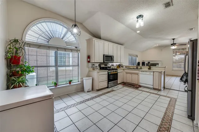 a kitchen with stainless steel appliances kitchen island granite countertop a sink a counter space cabinets and a living room view