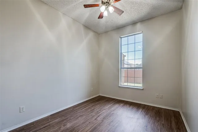 an empty room with wooden floor chandelier and window