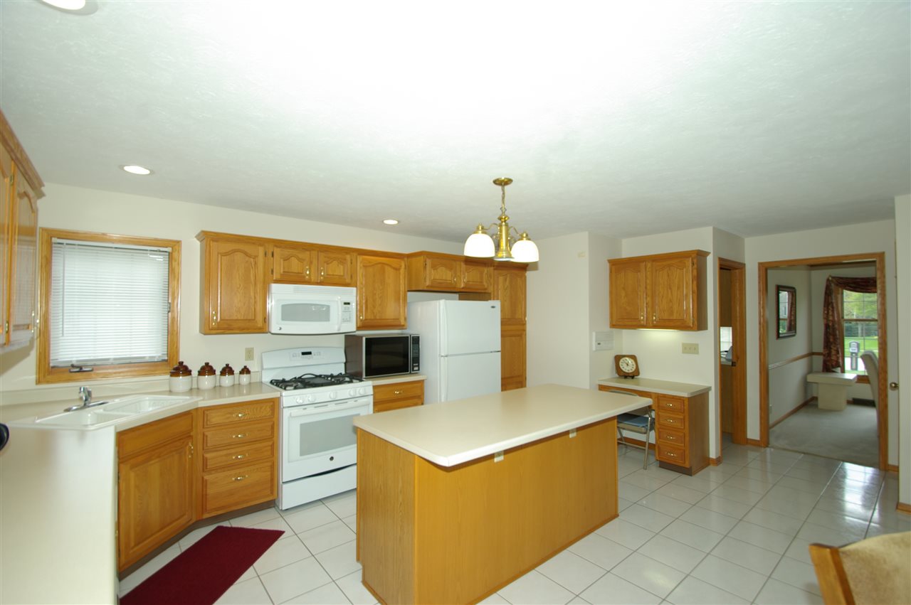 7254 Sentinel Road Rockford, IL 61107 - Photo 6 of 25 a large white kitchen with a stove a sink a refrigerator and chandelier