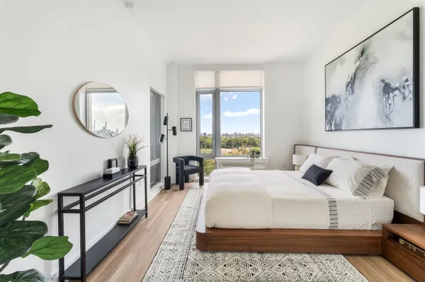 a bedroom with a bed a mirror and a large window with the garden view