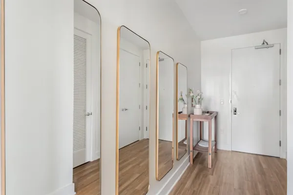 a view of a hallway with wooden floor and a bathroom