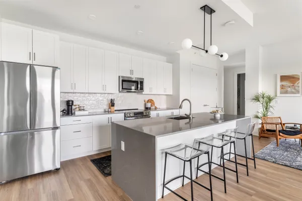 a kitchen with stainless steel appliances granite countertop a sink a stove a refrigerator and island with wooden floor