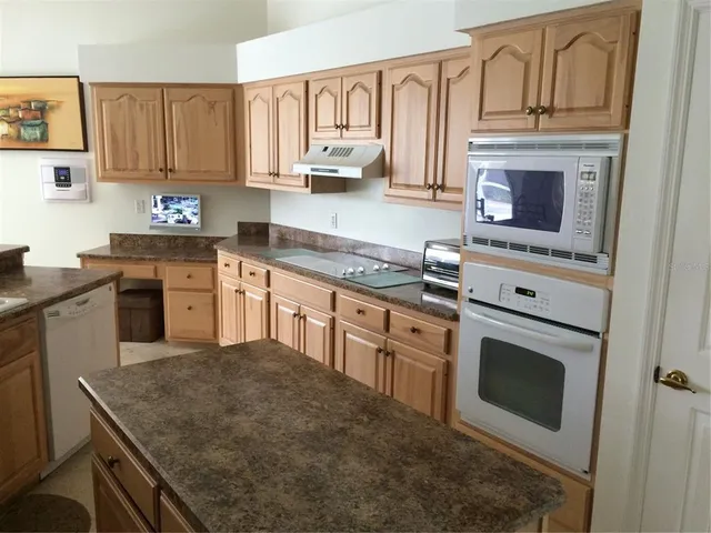 a large white kitchen with stainless steel appliances wooden cabinets and a counter top space