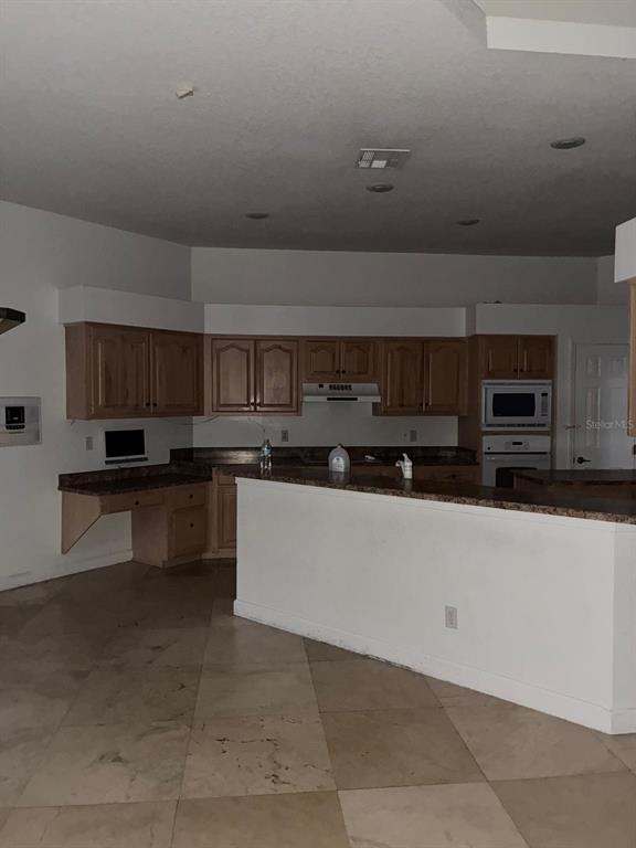 8125 Courtleigh Drive Orlando, FL 32835 - Photo 17 of 26 a large white kitchen with stainless steel appliances wooden cabinets and a counter top space