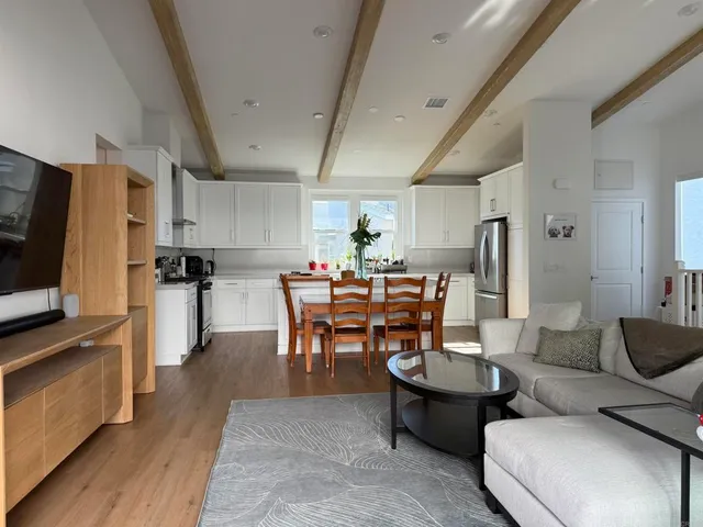 a living room with furniture a flat screen tv and kitchen view