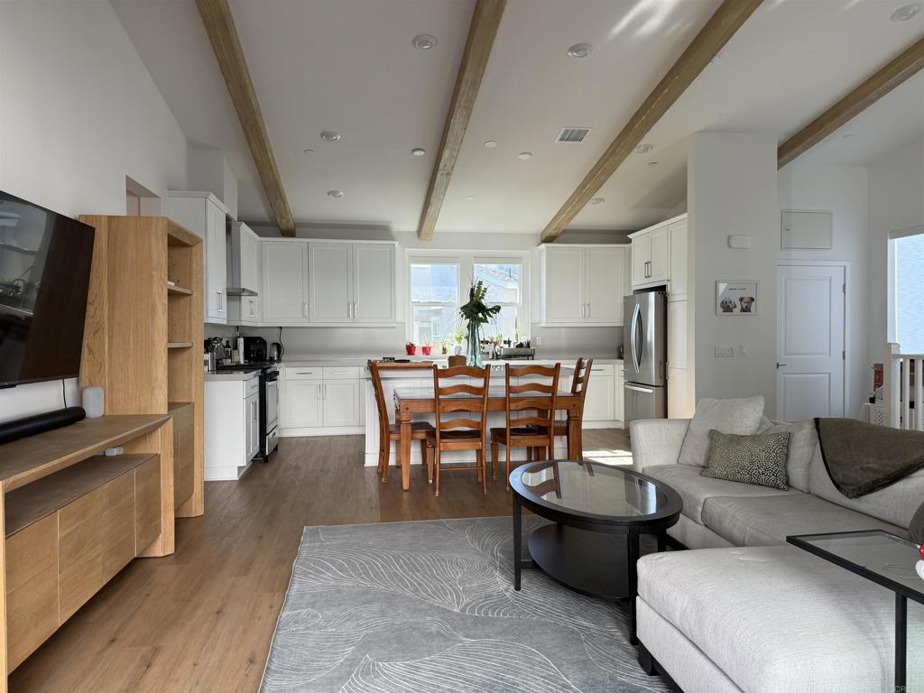 a living room with furniture a flat screen tv and kitchen view