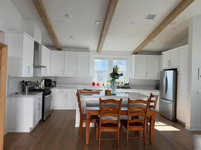 a kitchen with stainless steel appliances a dining table chairs refrigerator and cabinets