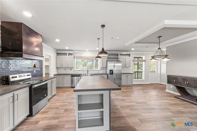 a kitchen with kitchen island a counter top space a sink stainless steel appliances and cabinets