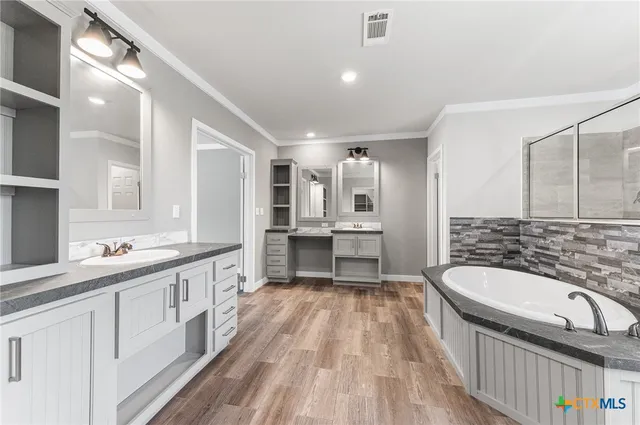 a bathroom with a granite countertop double vanity sink a mirror and a bathtub