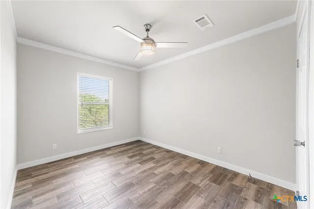 an empty room with a window and ceiling fan