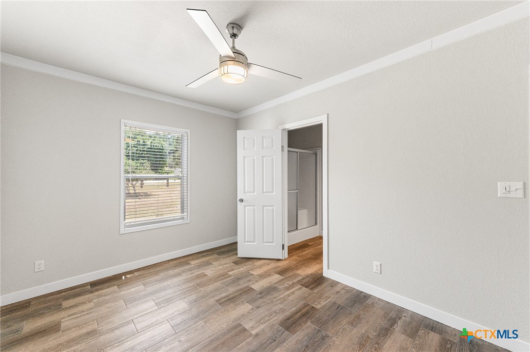 9130 Rebecca Creek Road Spring Branch, TX 78070 - Photo 27 of 41 an empty room with wooden floor ceiling fan and windows