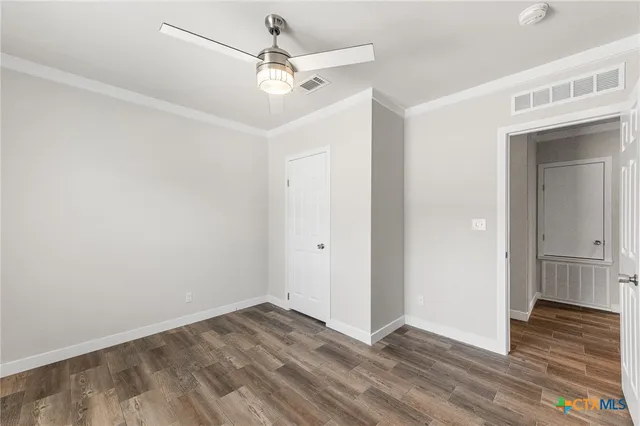 an empty room with wooden floor and ceiling fan