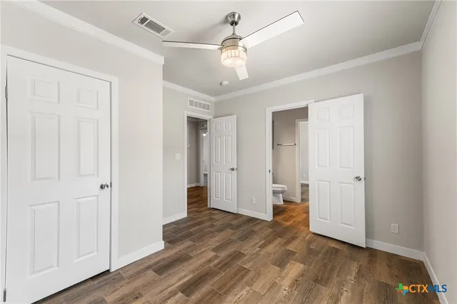 a view of a livingroom with a chandelier fan and wooden floor
