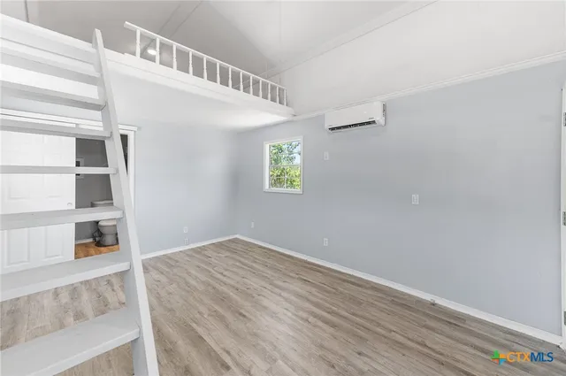 a view of an empty room with closet and wooden floor