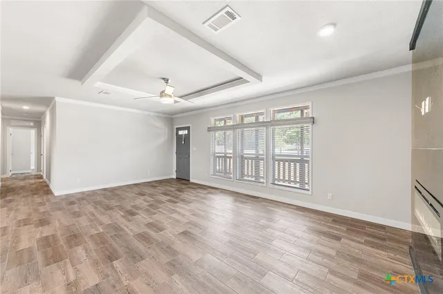 a view of an empty room with wooden floor and a window