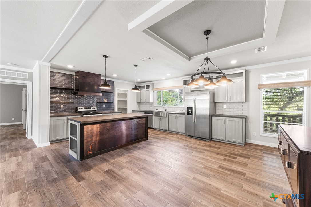 9130 Rebecca Creek Road Spring Branch, TX 78070 - Photo 8 of 41 a large kitchen with stainless steel appliances kitchen island granite countertop a large counter top and wooden floors