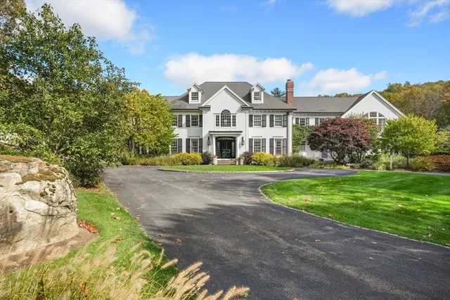a view of a white house next to a yard with big trees