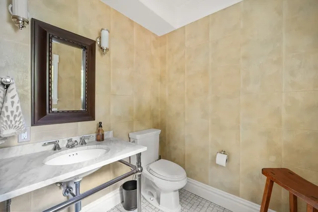 a bathroom with a granite countertop sink toilet and mirror