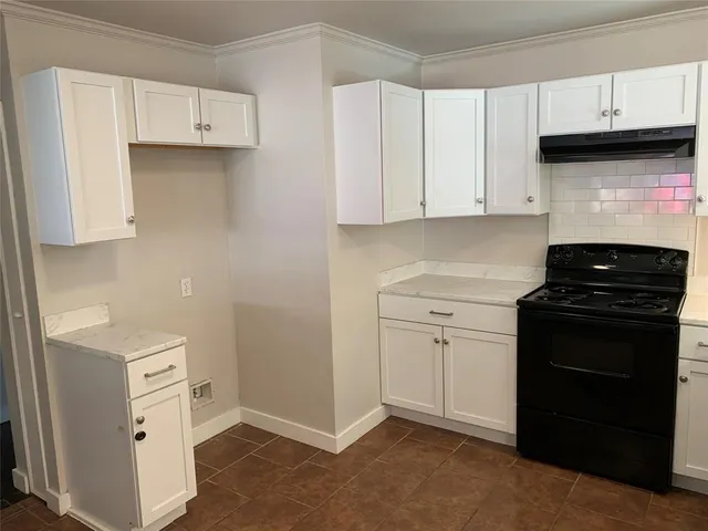 a kitchen with white cabinets and black appliances