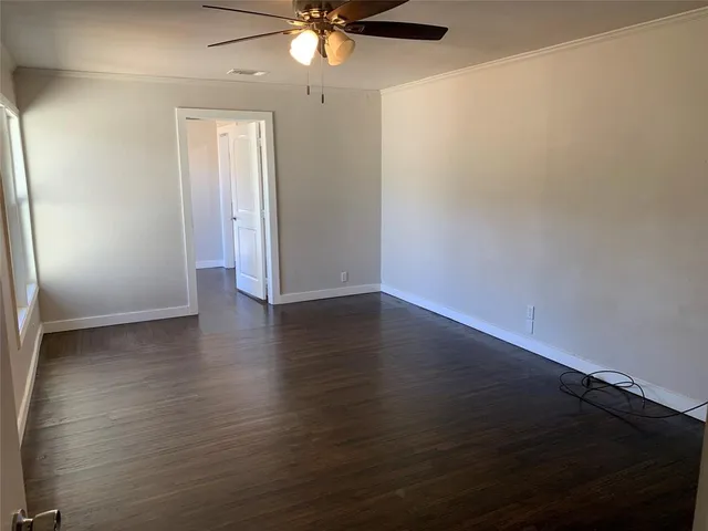 an empty room with wooden floor and fan