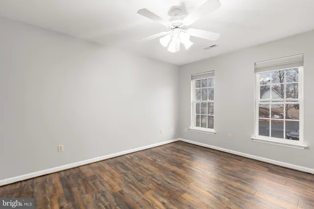 an empty room with wooden floor and a ceiling fan