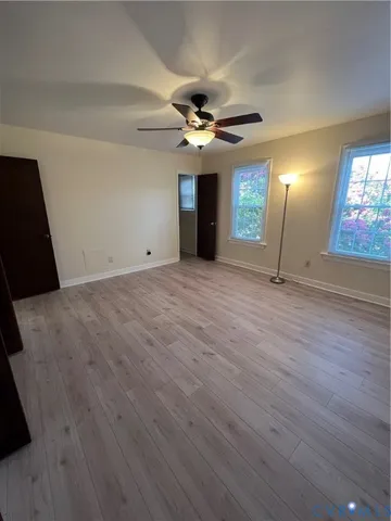 a view of an empty room with window and wooden floor