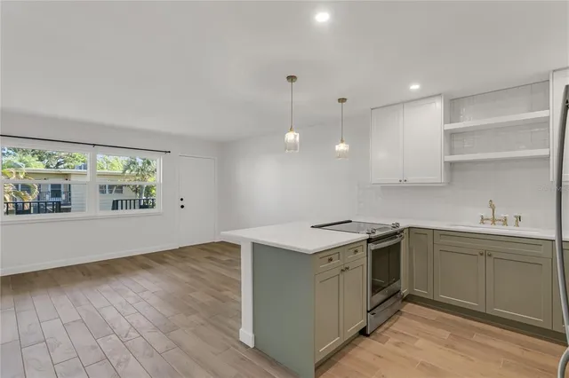 a kitchen with stainless steel appliances granite countertop a sink a stove and a wooden floors