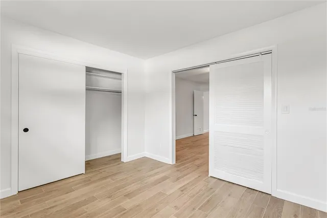 an empty room with wooden floor & closet area
