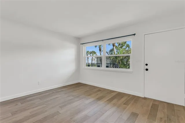 a view of an empty room with wooden floor and window