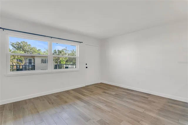 a view of an empty room with wooden floor and a window