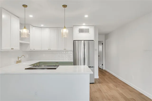 a kitchen with stainless steel appliances granite countertop a refrigerator a sink and white cabinets