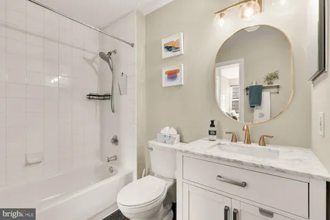 a bathroom with a granite countertop sink mirror vanity and toilet