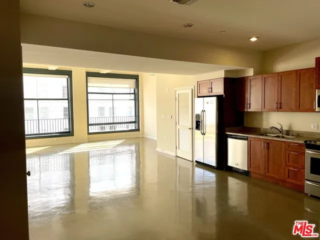 a large kitchen with stainless steel appliances granite countertop a refrigerator a stove and a large window