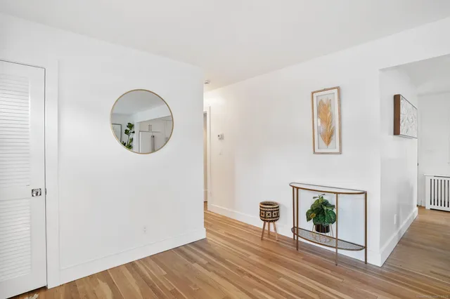 an empty room with wooden floor mirror and windows