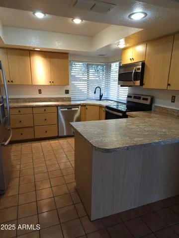 a large kitchen with stainless steel appliances a large counter top a stove a chimney a sink and a counter top space