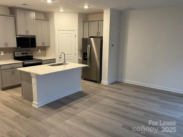 a kitchen with stainless steel appliances a stove refrigerator and a microwave