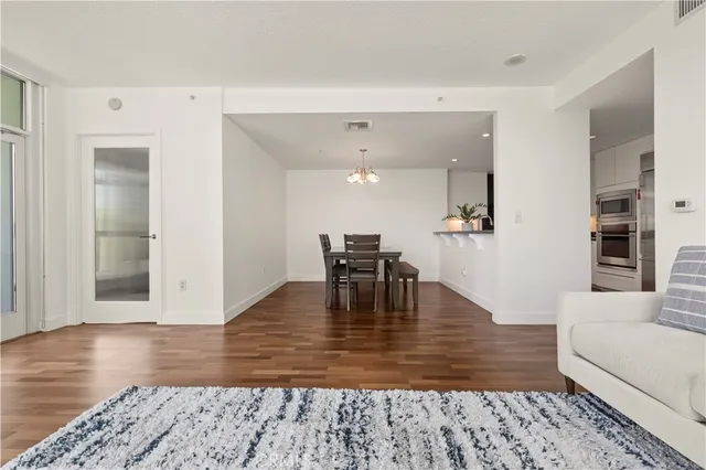 a living room with furniture and a dining table with wooden floor