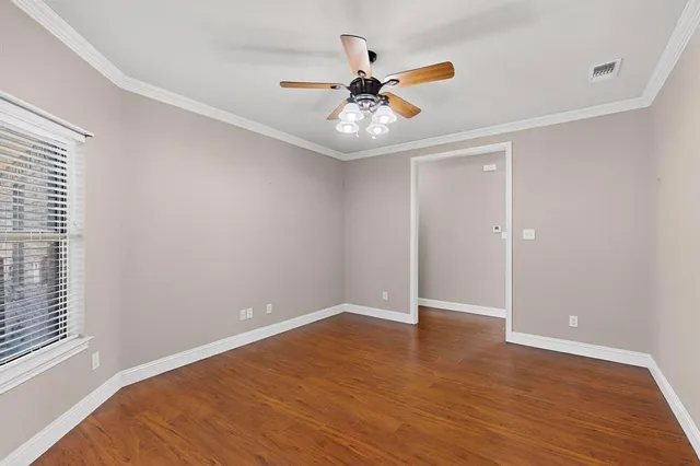 an empty room with wooden floor fan and windows