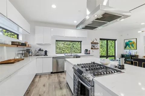 a kitchen with stainless steel appliances a dining table chairs and window