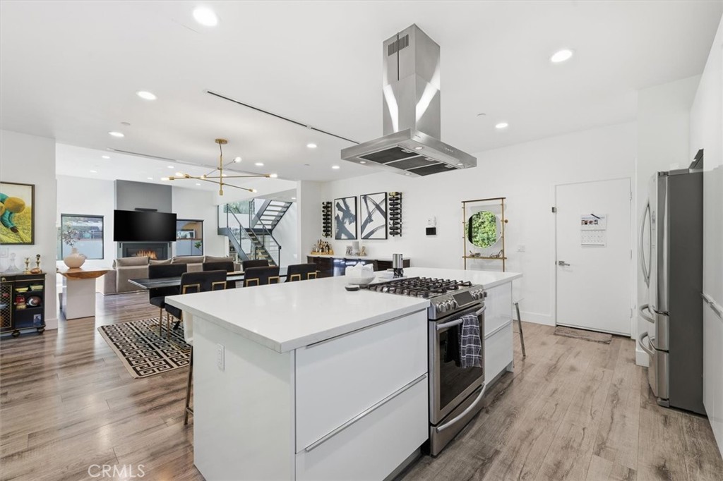 5487 Blanco Way Culver City, CA 90230 - Photo 12 of 58 a large kitchen with stainless steel appliances a stove a refrigerator a oven a sink with a dining table and chairs with wooden floor