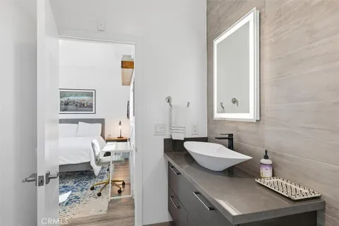 a spacious bedroom with a bed and a flat tv screen on dresser